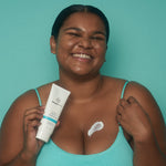 freezeframe BREAST ENHANCER cream texture applied to chest by woman holding product tube 